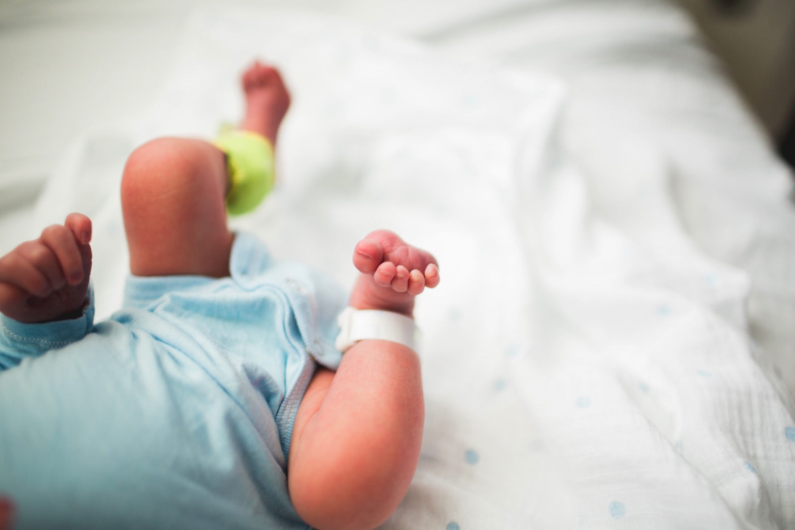 Legs of a baby laying on a hospital bed with tags on their ankle