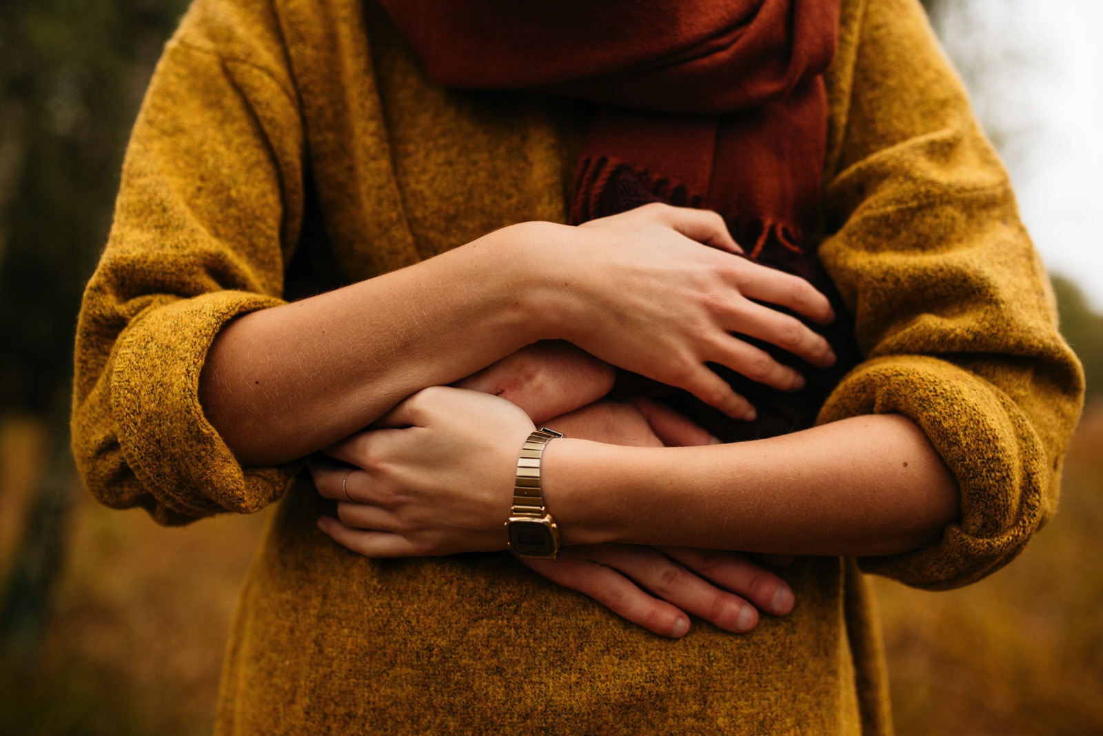 Couple's arms wrapped around stomach of woman