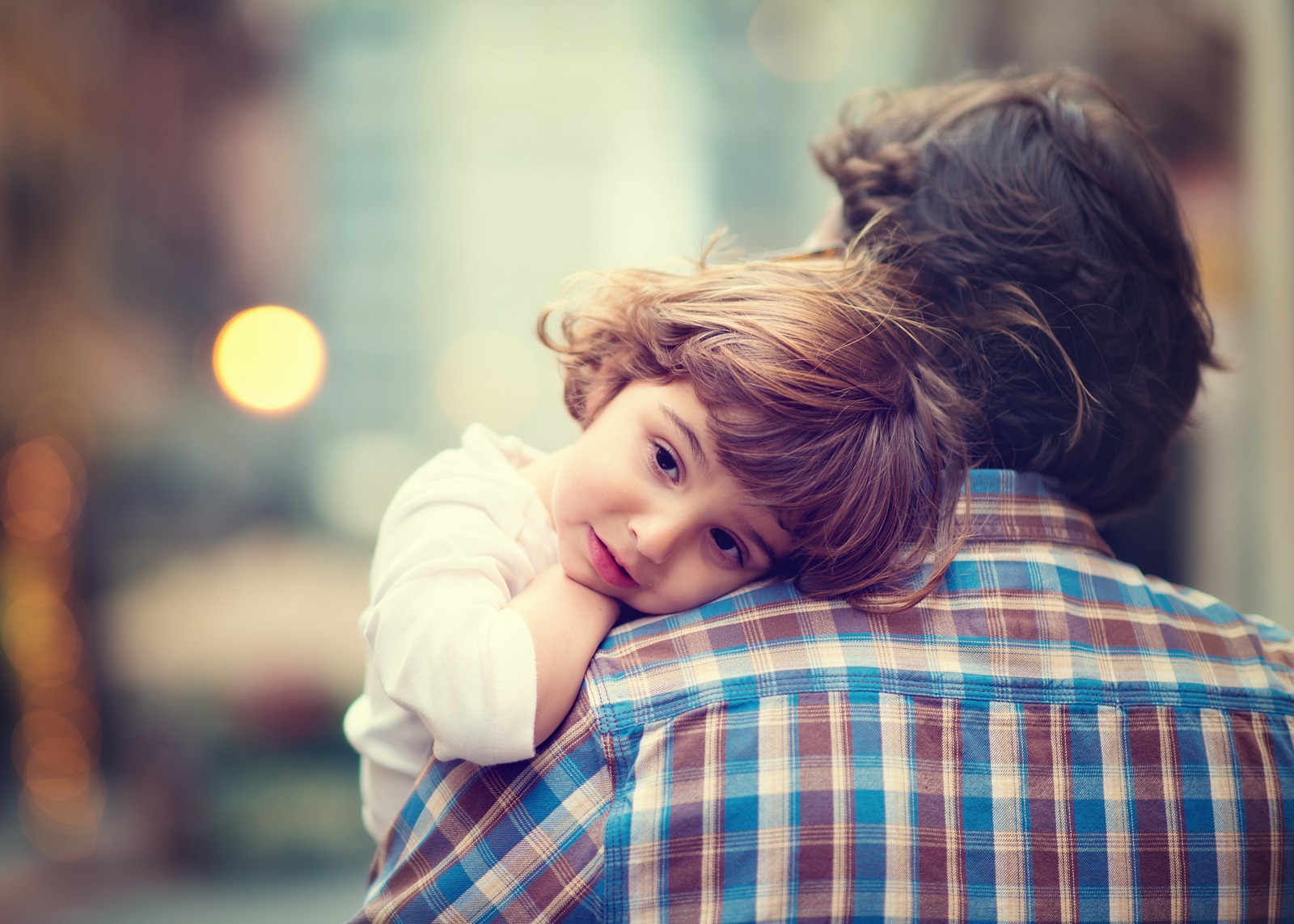 Young child resting head on man's shoulder