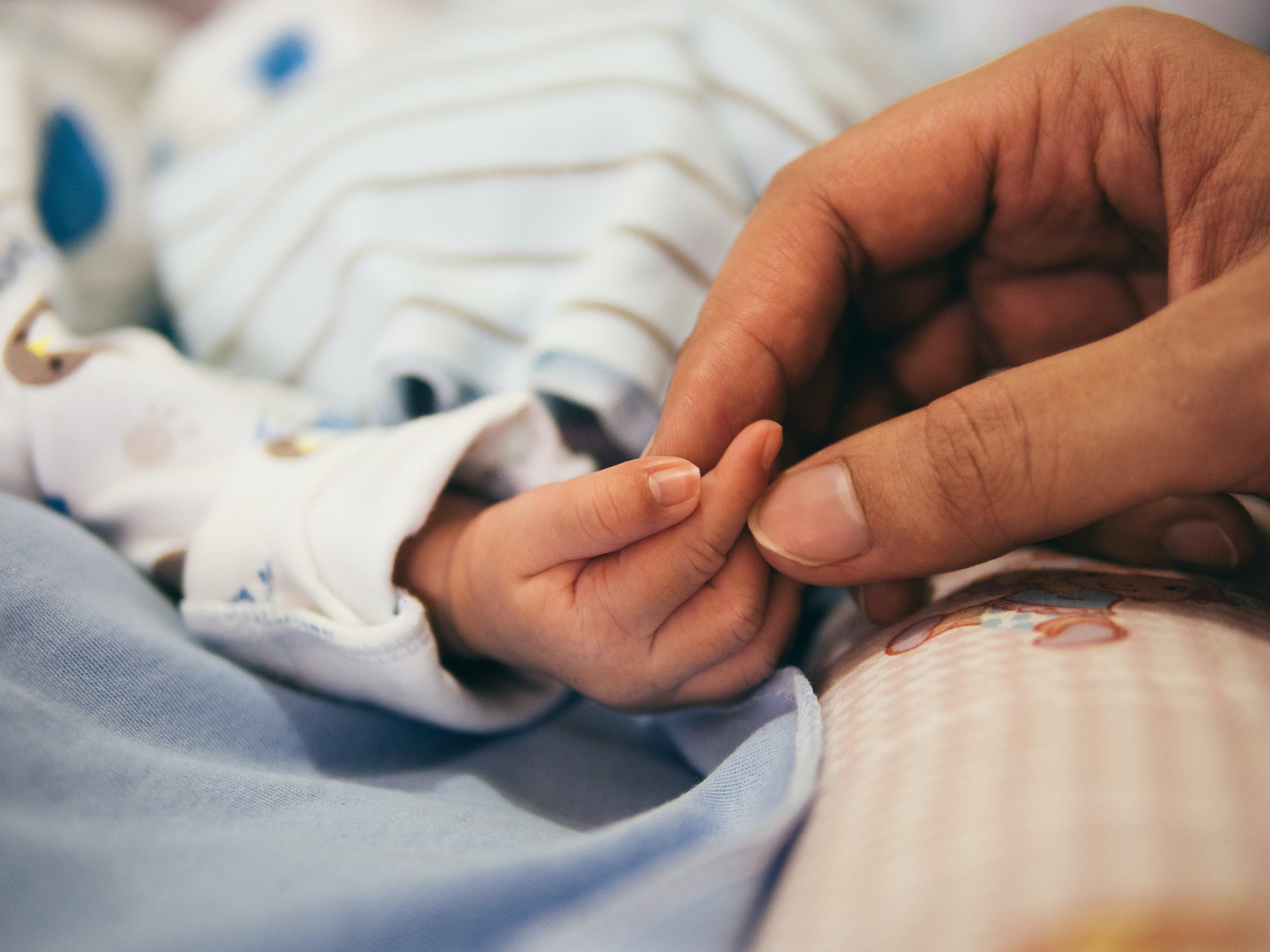 Baby holding woman's hand