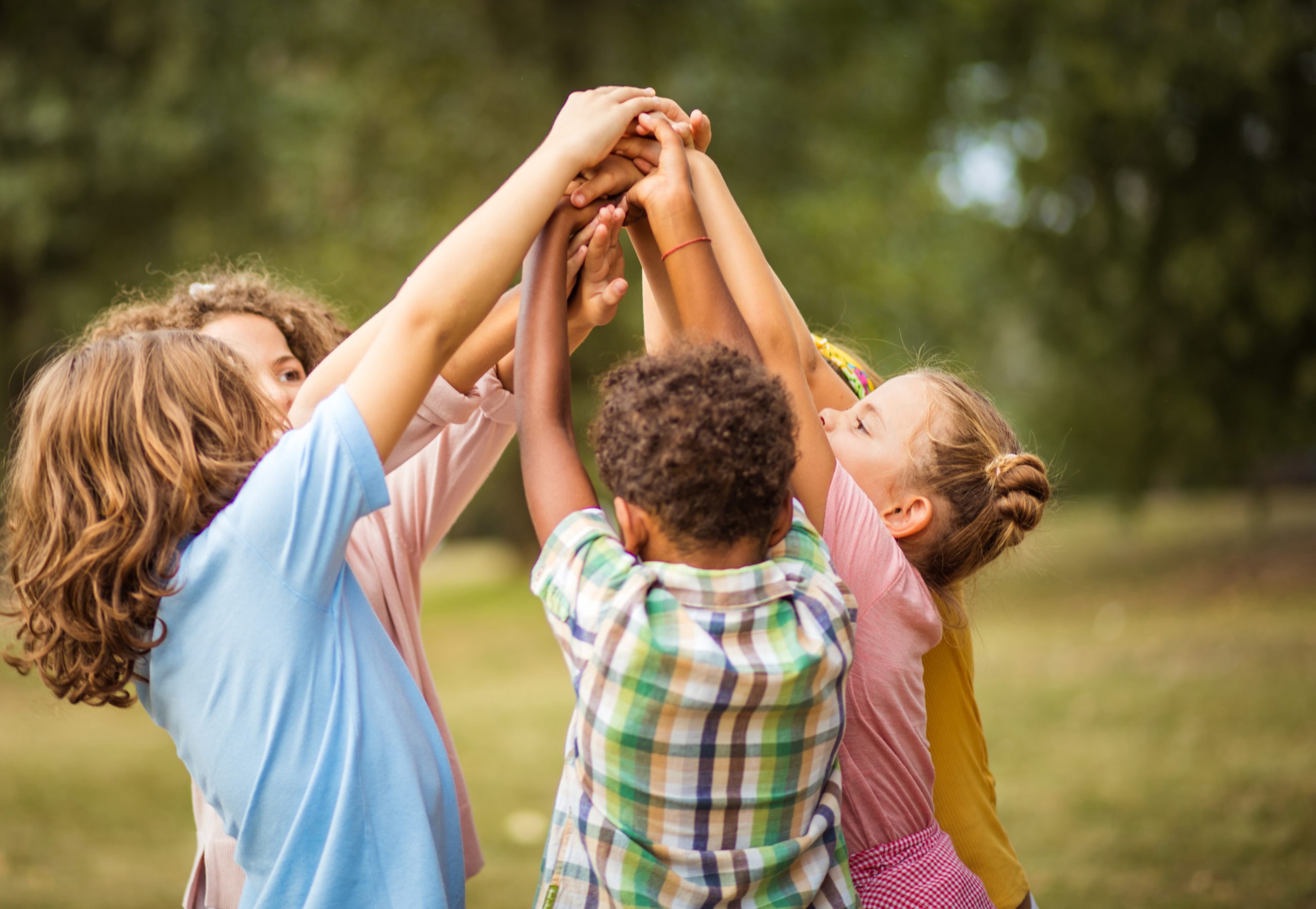 Group of young children with hands clasped together in the air