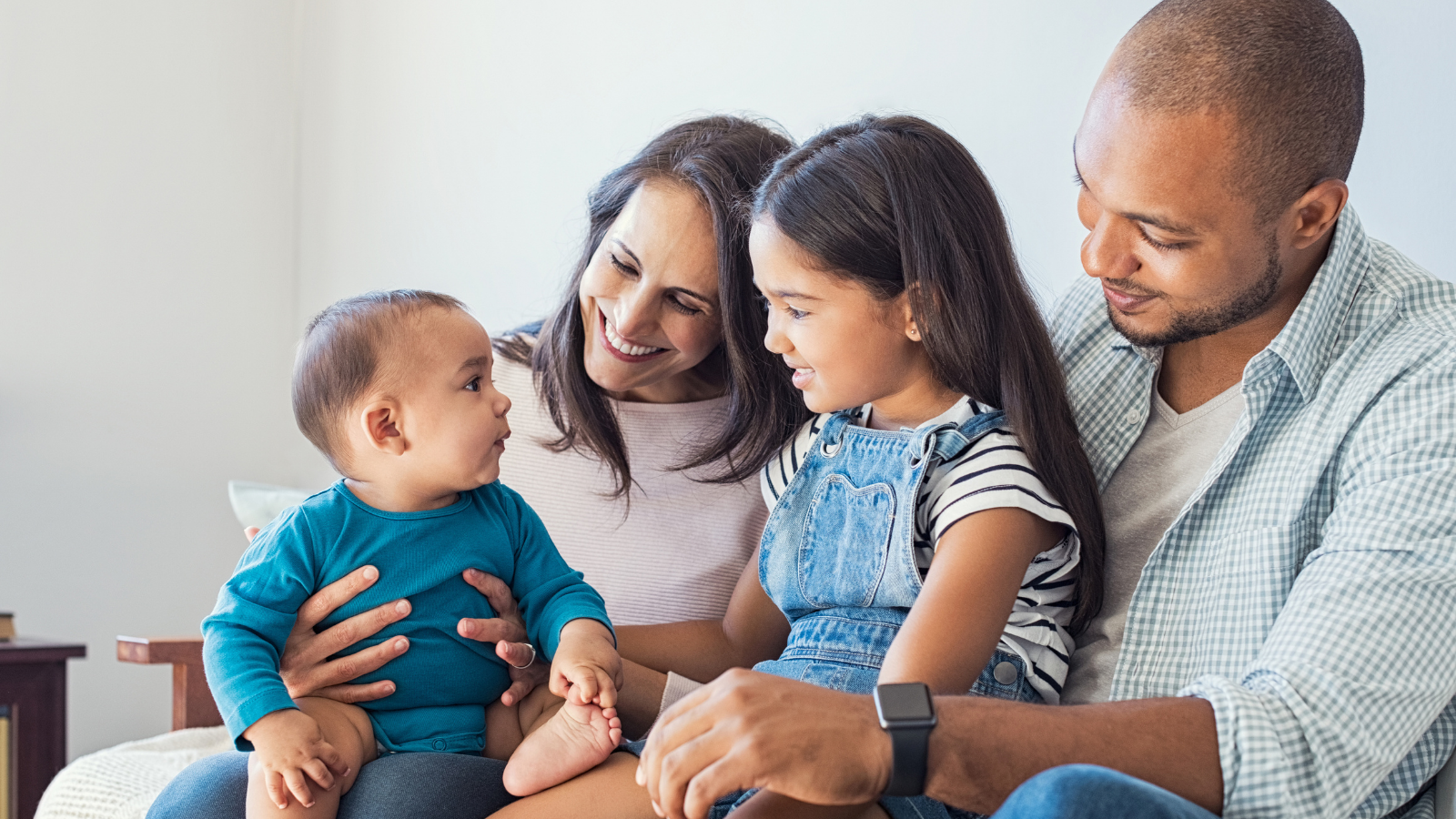 Couple with two young children, smiling at the baby on the mother's knee