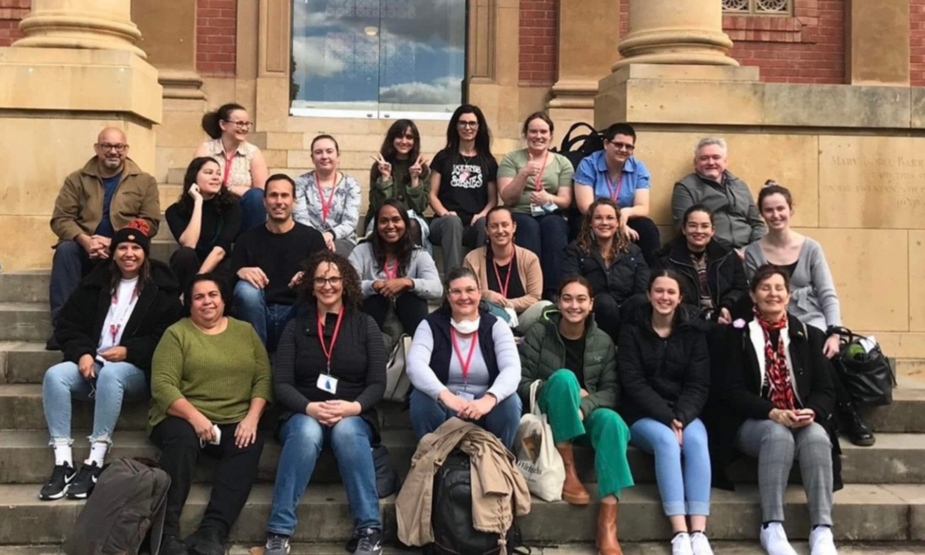 Group photo of participants of SING Australia workshop sitting on the steps of a building