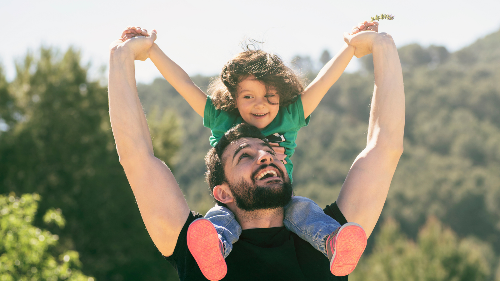 A young boy sits on his father's shoulders.