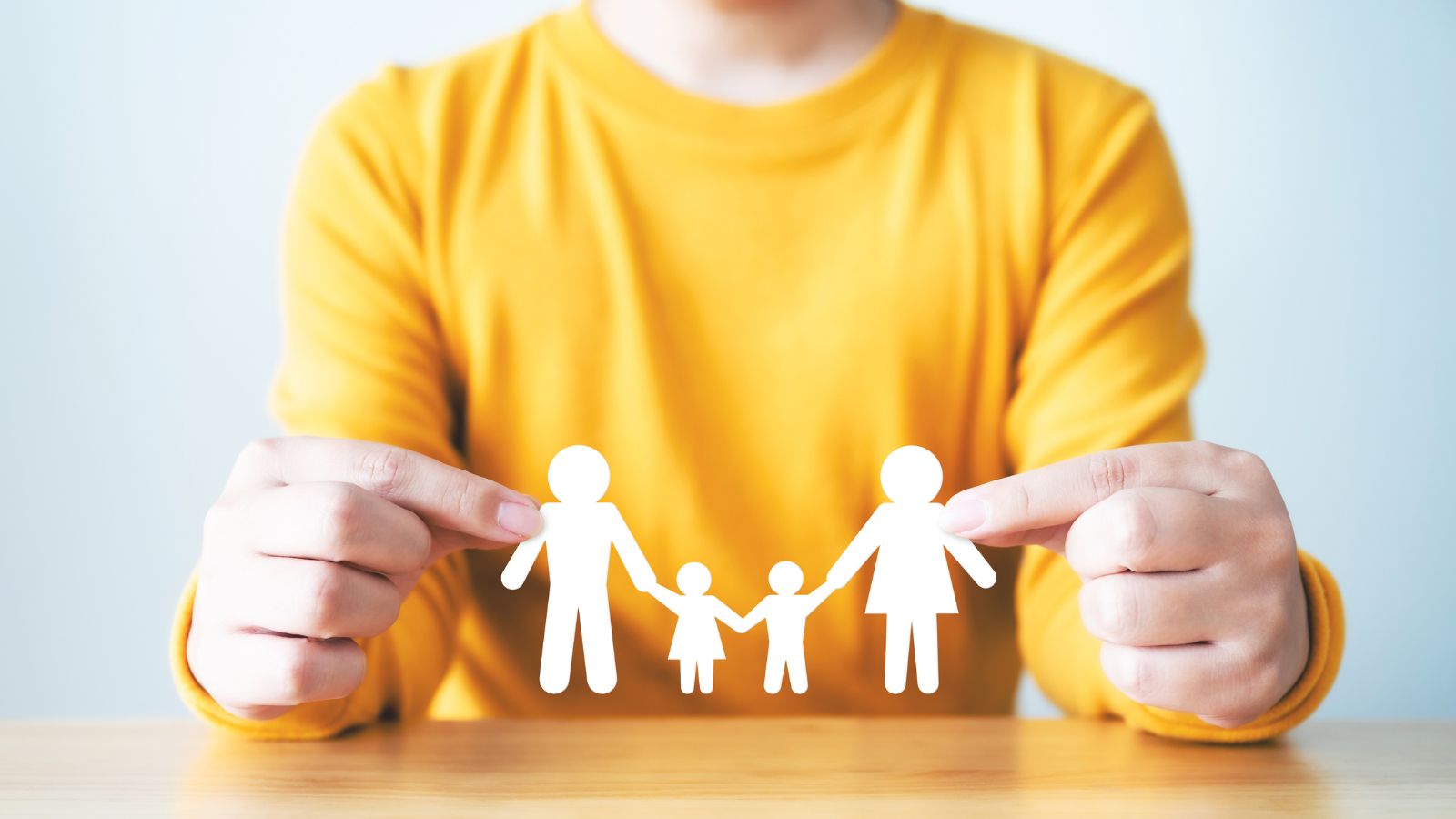 Image of a person holding a paper cut out of a family