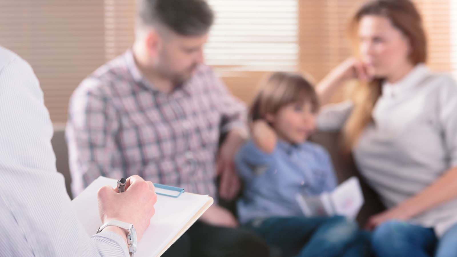 Male hands completing paperwork with a family in the background